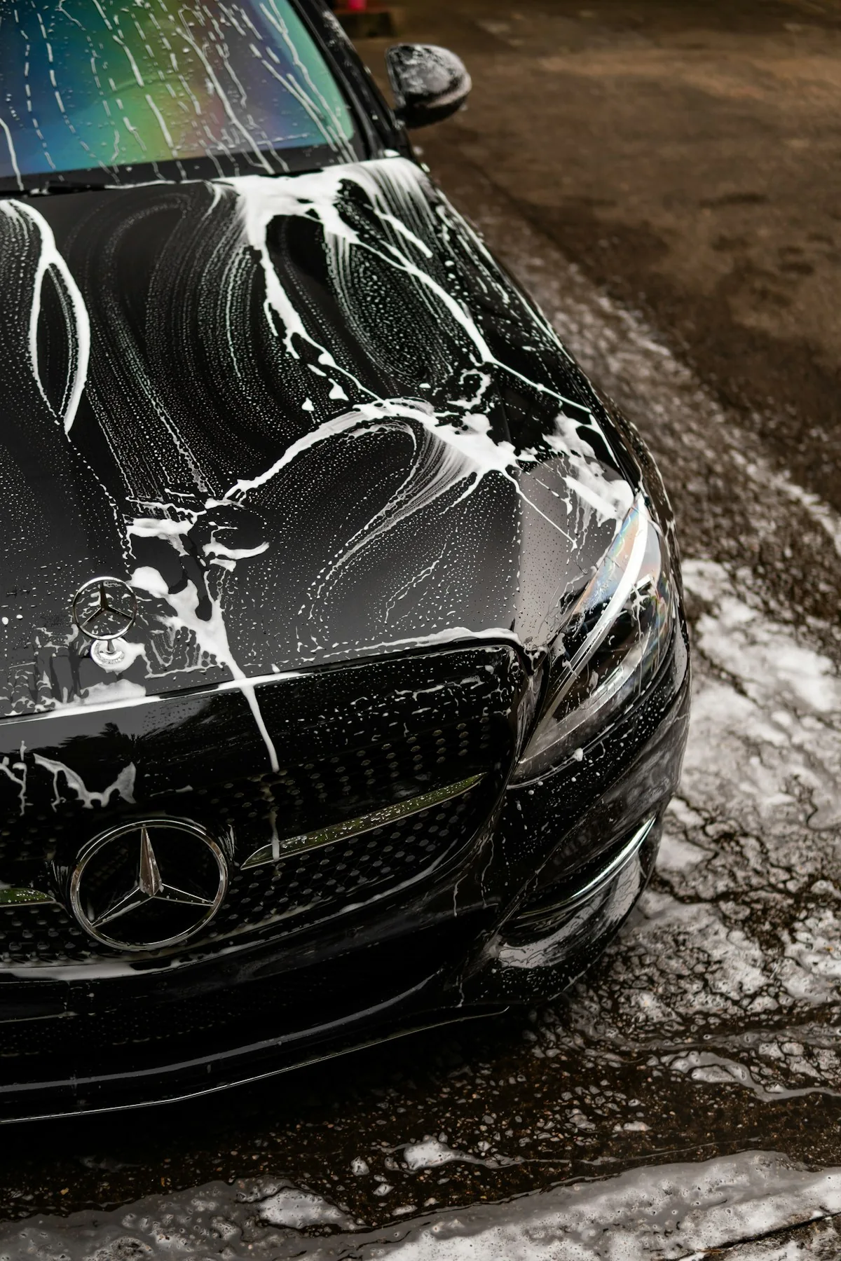 Illustrative stock photograph of a black car covered in wash foam